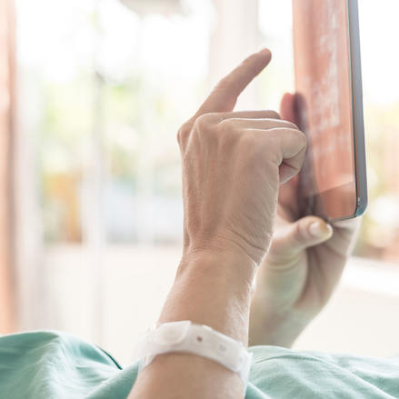 Patient in hospital room using a tablet.